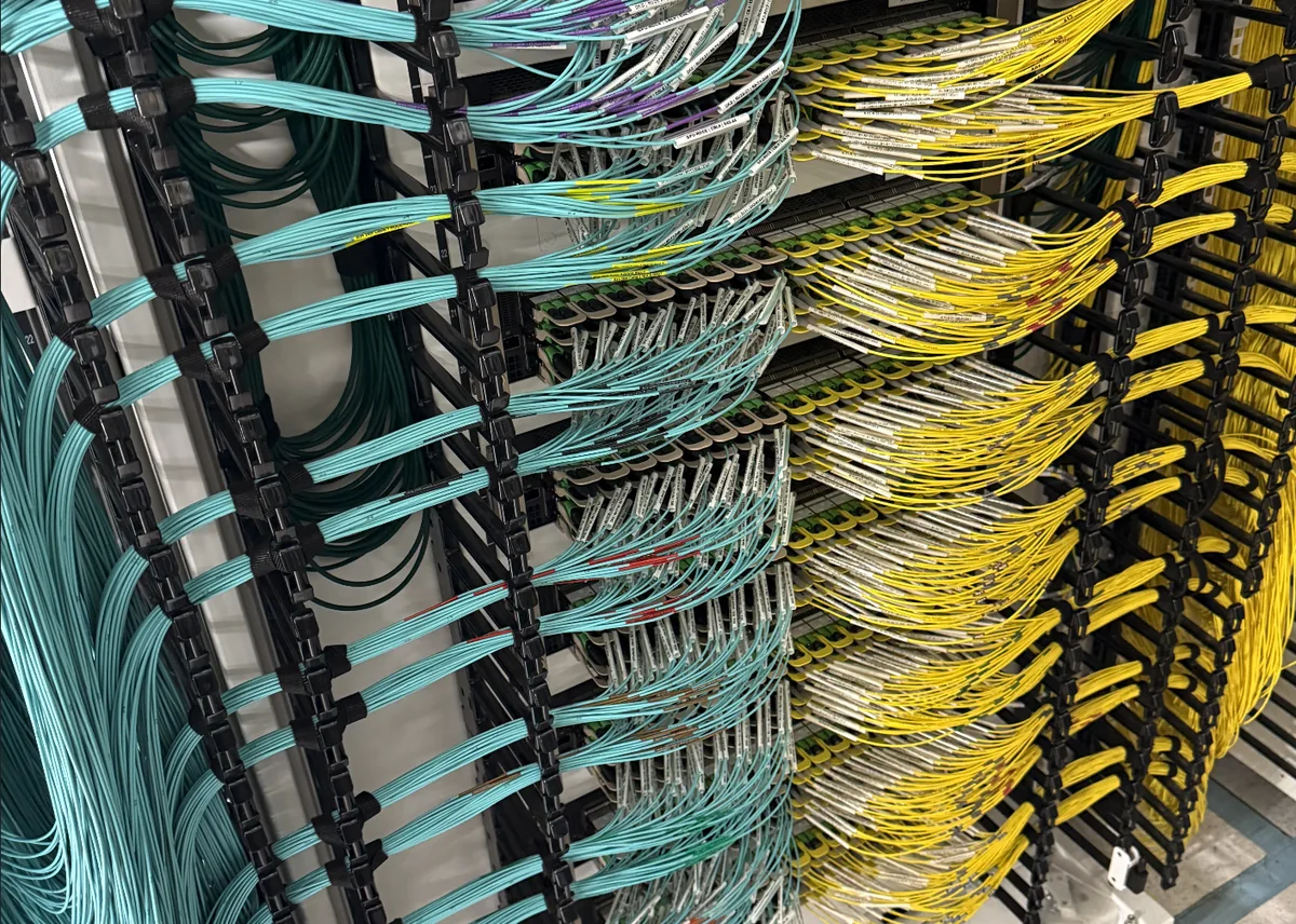 Labeled aqua and yellow fiber cables organized in equipment racks