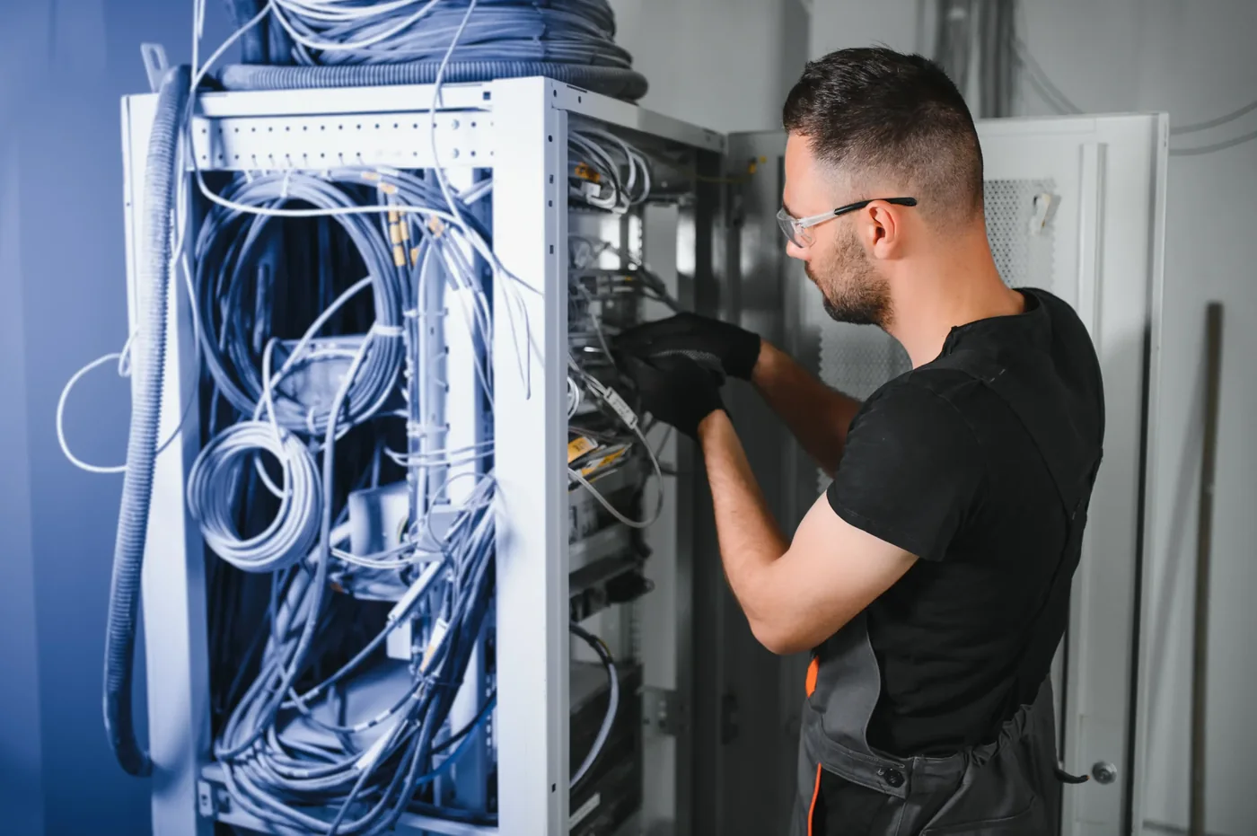Technician working on cabling inside a network equipment cabinet